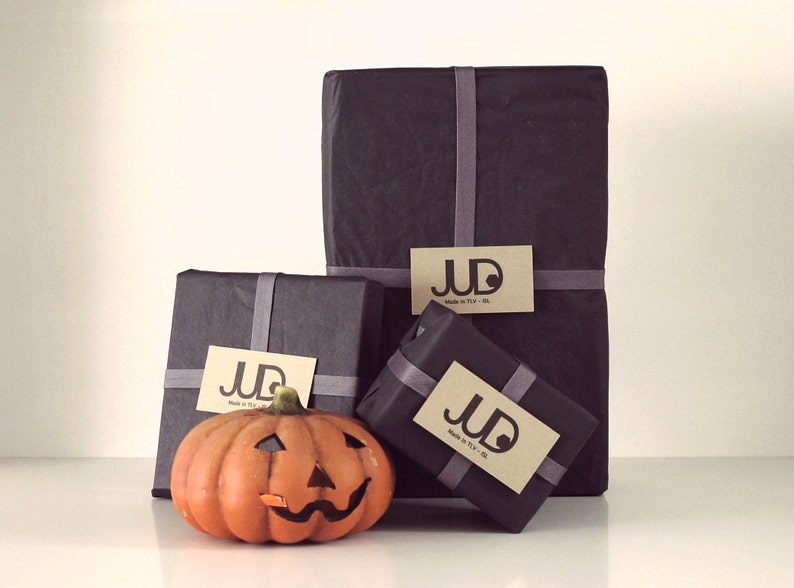 May include: Three black gift boxes with brown paper labels that say "JUD Made in Italy - NY - LA" and a small orange jack-o'-lantern.