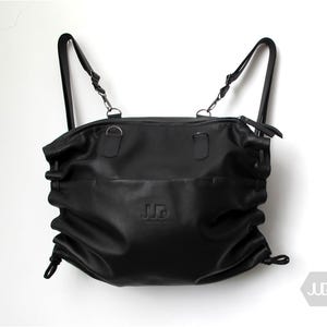 May include: Black leather backpack with adjustable straps and a drawstring closure. The bag has a  'JUD' logo embossed on the front.