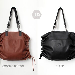May include: Two leather tote bags with adjustable straps. The bag on the left is cognac brown and the bag on the right is black. Both bags have the word "JUD" embossed on the front.