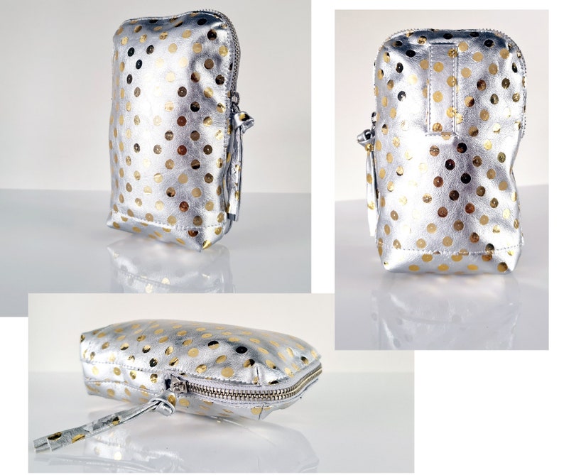May include: A silver and gold polka dot makeup bag with a zipper closure and a tassel pull. The bag is laying flat on a white surface.
