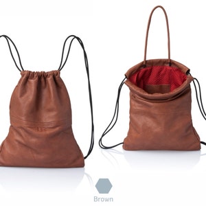 May include: A brown leather drawstring backpack with black straps. The backpack can also be carried by the top handle. The inside of the bag is lined with red fabric.