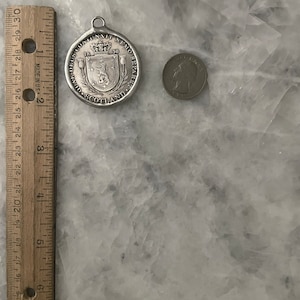 May include: A silver-toned medal with a crown and the text "DEUS CONIUNXIT NEMO SEPARETO" around the edge. The medal also has the text "SCOTLAND" and the year "1630" on it.