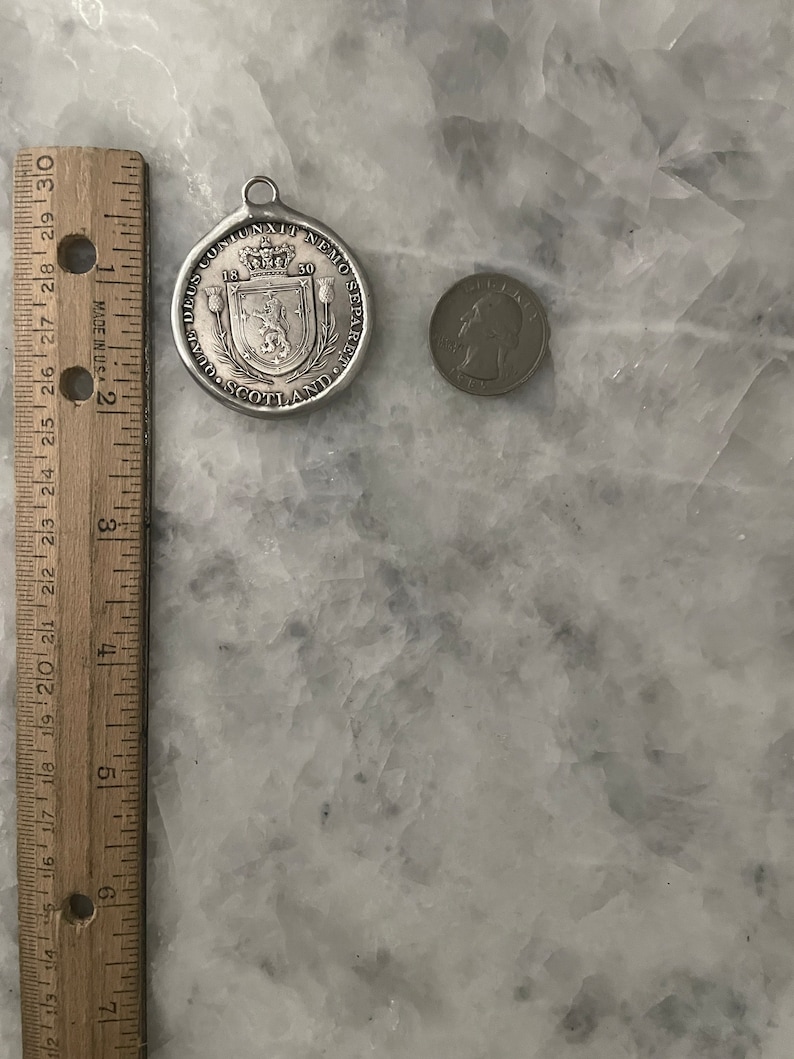 May include: A silver-toned medal with a crown and the text "DEUS CONIUNXIT NEMO SEPARETO" around the edge. The medal also has the text "SCOTLAND" and the year "1630" on it.