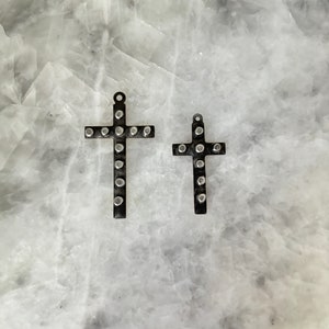 May include: Two silver crosses with a studded design. The crosses are different sizes and are on a white background.