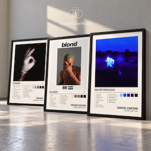 May include: Three framed music album posters featuring Drake's Iceman with a hand graphic, Frank Ocean's Blond with a portrait, and Daniel Caesar's Never Enough with a blue landscape. Each print includes tracklists and artist names.