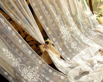 May include: White crochet curtains with a delicate floral pattern. The curtains are made of a lightweight, airy fabric and have a soft, romantic feel.