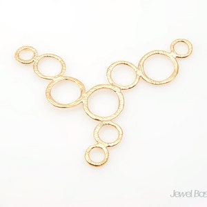 Peut inclure: Pendentif en métal doré avec un motif de cercles interconnectés. Le pendentif a une finition texturée et est en forme de Y.