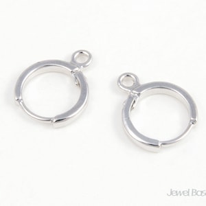 Op de afbeelding: Twee zilveren oorringbevestigingen met een springring bevestigd aan de bovenkant van elke ring.
