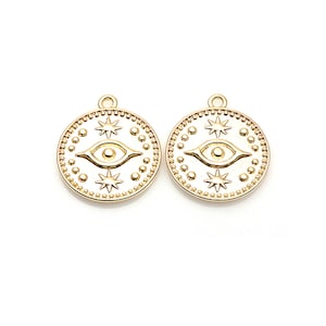 May include: Two gold-toned metal charms in the shape of a circle with an evil eye design and stars.
