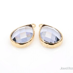 May include: Two gold teardrop-shaped pendants with clear faceted glass inserts.