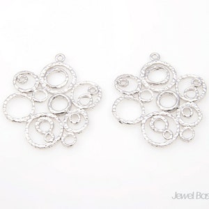 May include: Two silver-toned metal pendant charms with a design of overlapping circles. The circles have a textured surface.