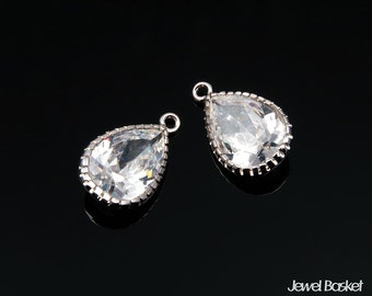 May include: Two silver teardrop-shaped crystal charms with a clear, faceted design. The charms have a loop at the top for attaching to jewelry.
