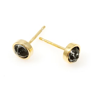 May include: A pair of gold stud earrings with black diamond accents.