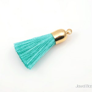 May include: A turquoise blue tassel with a gold metal top. The tassel is made of soft, silky threads and is perfect for adding a touch of elegance to any project.