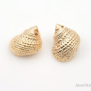 以下が含まれることがあります： 金色の貝殻の形をしたイヤリングが2つ。貝殻は表面がざらざらしていて、イヤリングポストに取り付けるための穴が上部に開いています。