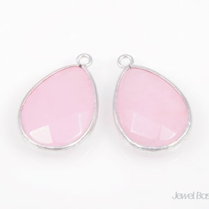May include: Two pink teardrop-shaped gemstone pendants with silver settings. The pendants have a smooth, polished finish and are perfect for jewelry making.