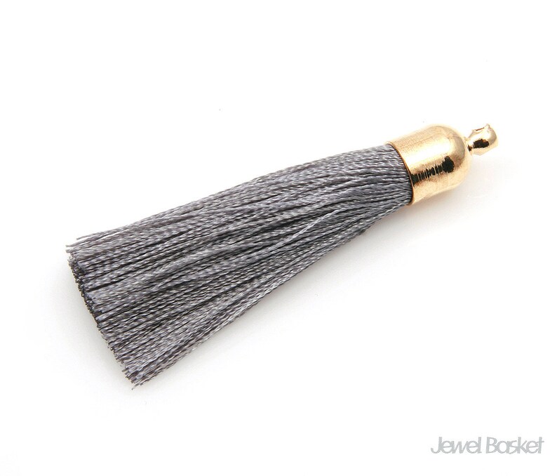 May include: A gray tassel with a gold metal top. The tassel is made of soft, silky threads.