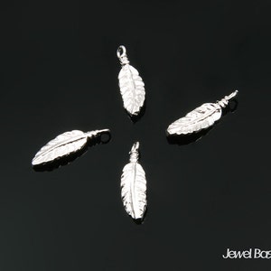 May include: Four silver feather charms with a loop at the top for attaching to jewelry. The feathers are detailed with a textured design.