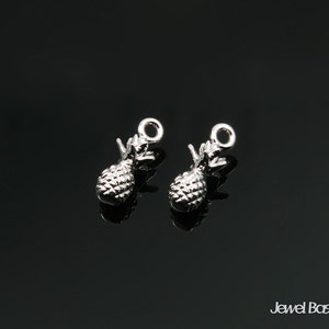 May include: Two silver pineapple charms with a loop at the top for attaching to jewelry or other crafts.