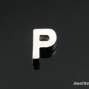 May include: Silver charm in the shape of the letter P. The charm is a single letter, and is made of metal.