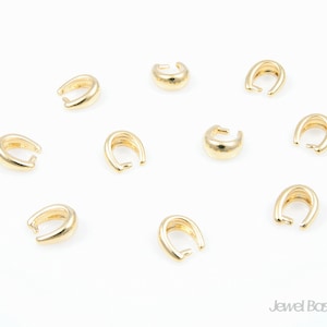 Peut inclure: Dix perles à sertir en métal doré pour la fabrication de bijoux. Les perles sont en forme de petite boucle ouverte.