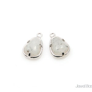 May include: Two silver teardrop-shaped pendants with clear, cloudy, white stones set in the centre.