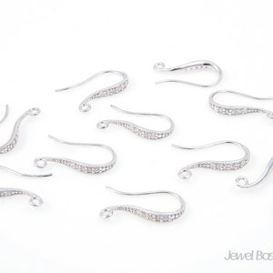 May include: Ten silver earring hooks with clear crystal accents. The hooks are curved and have a small loop at the top.