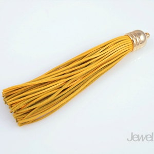 May include: A yellow leather tassel with a gold metal top. The tassel is about 6 inches long.