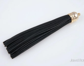 May include: Black leather tassel with a gold metal top. The tassel is about 6 inches long.