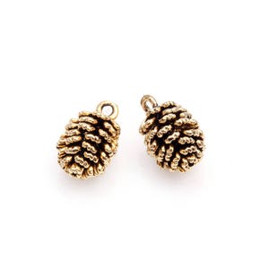 May include: Two gold-toned metal pine cone charms with a loop at the top for attaching to jewellery or other crafts.