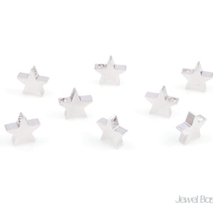 Puede incluir: Ocho abalorios de estrella plateados con un cristal transparente en el centro. Los abalorios tienen un agujero en la parte superior para sujetarlos a joyas.