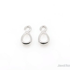Puede incluir: Dos anillos de salto de plata en forma de lágrima con un gancho en la parte superior. Estos anillos se utilizan para la fabricación de joyas.