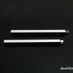 Puede incluir: Dos barras de metal plateado con extremos redondeados. Las barras miden aproximadamente 5 cm de largo y tienen un acabado liso y pulido.