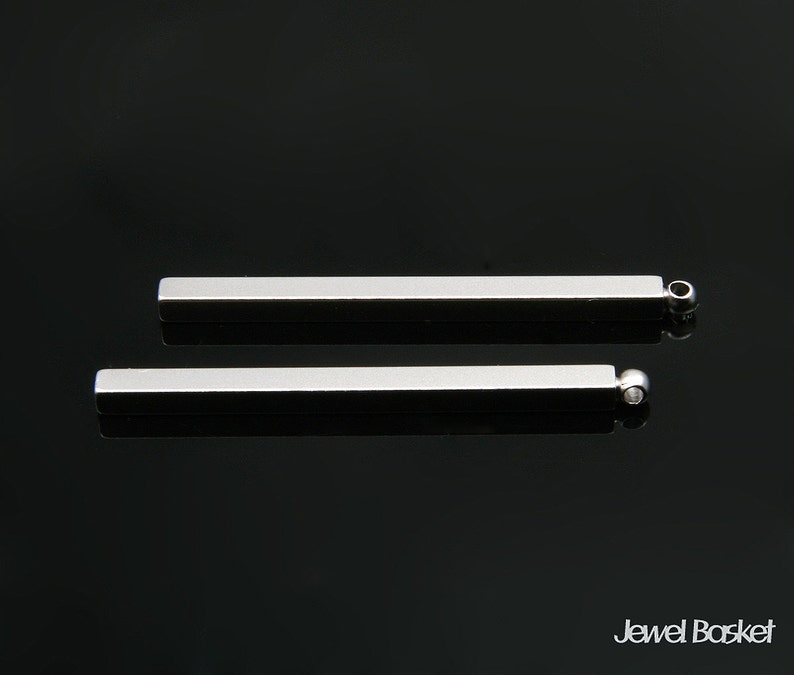 Puede incluir: Dos barras de metal plateado con extremos redondeados. Las barras miden aproximadamente 5 cm de largo y tienen un acabado liso y pulido.