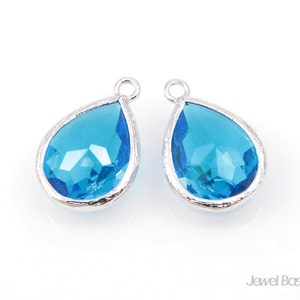 May include: Two silver teardrop-shaped pendants with blue crystal accents.