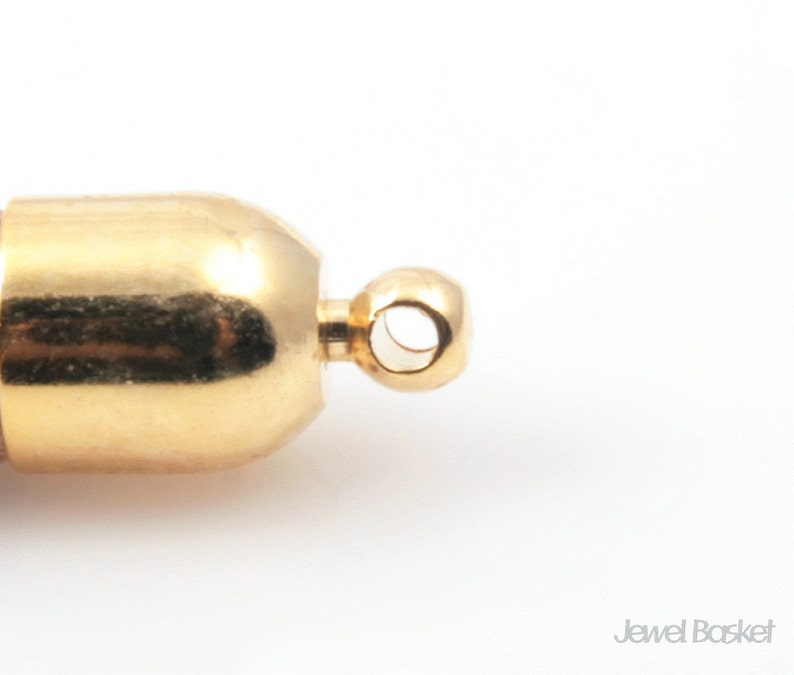 May include: Gold-toned metal end cap with a round loop for attaching a necklace or bracelet. The end cap has a smooth, polished finish.