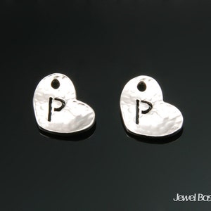 May include: Two silver heart-shaped charms with a hammered texture. Each charm has a letter 'P' cut out of the centre.