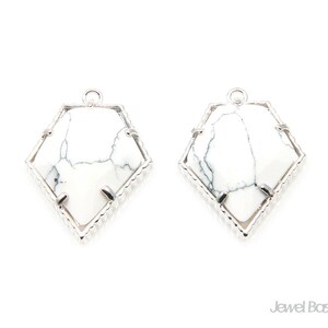 Peut inclure: Une paire de boucles d'oreilles en argent avec des accents de pierre de howlite blanche. Les boucles d'oreilles sont en forme de diamant avec un bord texturé.