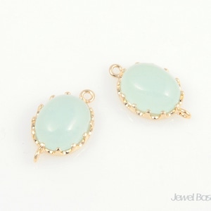 May include: Two gold-tone oval-shaped pendant charms with a light green glass cabochon stone. Each charm has a loop for attaching to a necklace or bracelet.