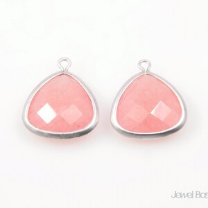 May include: Two pink gemstone pendants with silver settings. The gemstones are faceted and have a triangular shape.