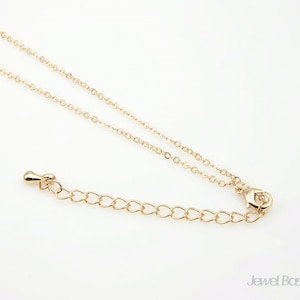 Puede incluir: Un collar de cadena dorada con cierre de mosquetón. La cadena está hecha de pequeños círculos unidos.