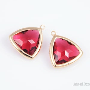 May include: Two gold-toned triangle-shaped pendants with red crystal accents.