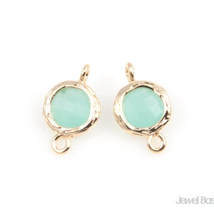 May include: Two gold-toned metal bead caps with a light green glass bead in the centre. Each cap has a loop on the bottom for attaching to jewellery.