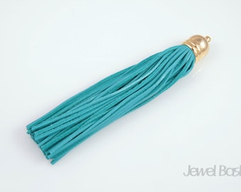 May include: Teal leather tassel with a gold metal top. The tassel is about 6 inches long.