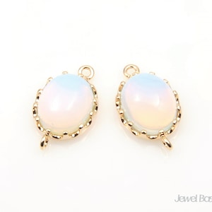 May include: Two gold oval-shaped pendant charms with a white opal-like stone in the center. The charms have a decorative gold border.