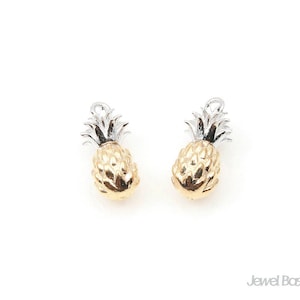 May include: A pair of gold and silver pineapple charm earrings. The pineapples are detailed with a textured surface and a silver top.