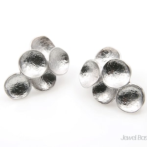 May include: A pair of silver earrings with a cluster of five round, textured discs. The discs are arranged in a cascading pattern, creating a unique and modern look.
