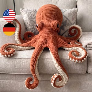 May include: A large, crocheted octopus plush toy featuring a textured, burnt-orange yarn body and head. The underside of each of the eight tentacles is a contrasting cream-colored yarn, detailed with small, raised, circular suction cups.