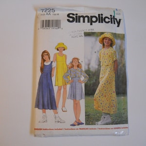 May include: Simplicity sewing pattern number 7225 for girls' dresses in sizes 7, 8, and 10. The pattern includes three different dress styles: a blue dress with a bib, a yellow dress with a sleeveless bodice, and a yellow dress with a floral print and a short-sleeved top.