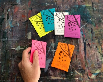May include: Five colorful cards with black ink drawings of trees and the word "Landscapes" written on each card.